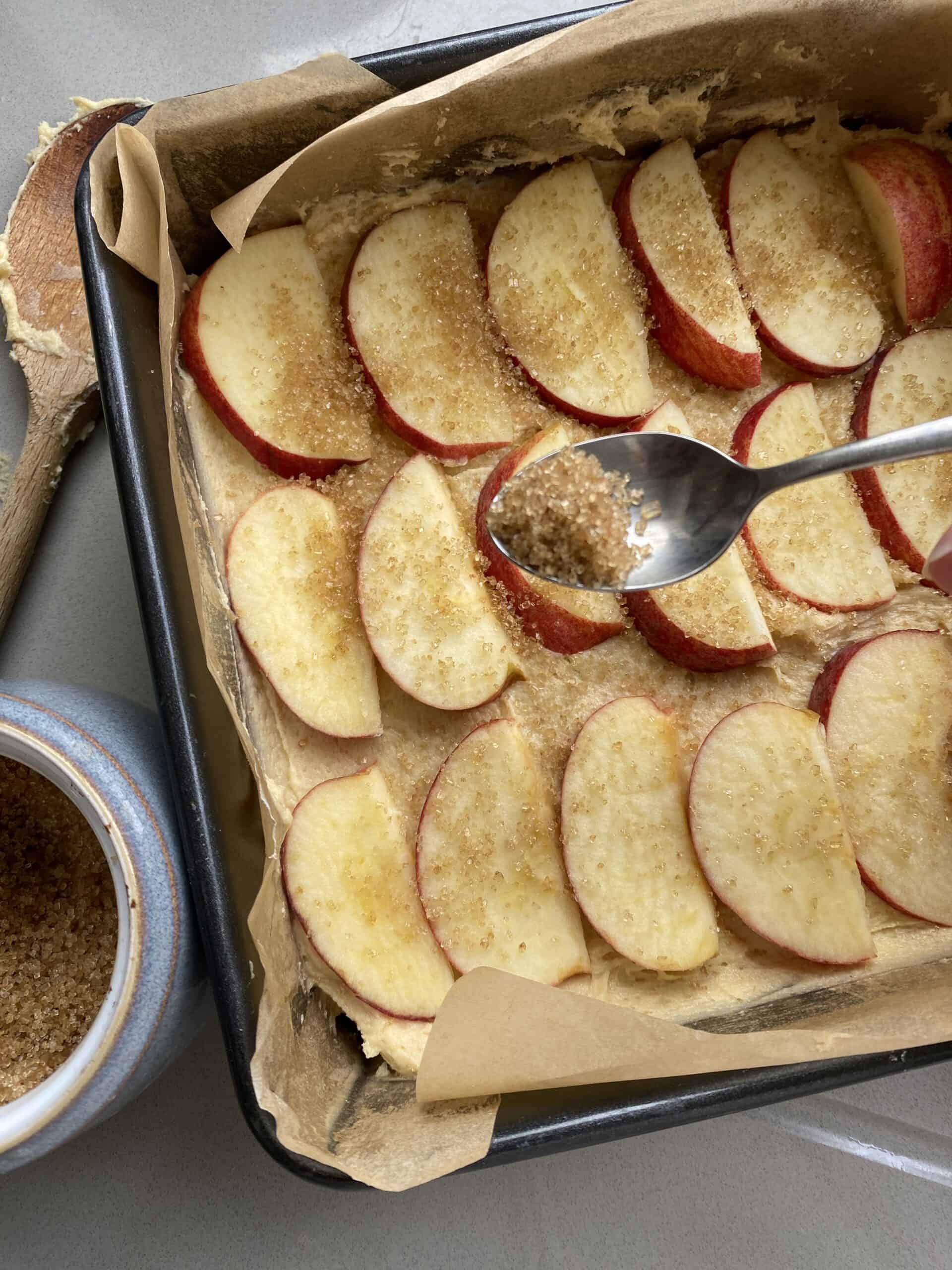 Dorset Apple cake batter with slices of apple in a baking tin.