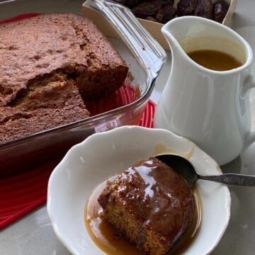 Sticky Toffee and Date pudding with a portion cut out and poured with toffee sauce.