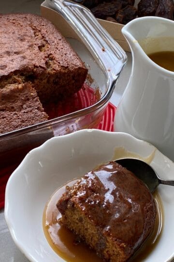 Sticky Toffee and Date pudding with a portion cut out and poured with toffee sauce.