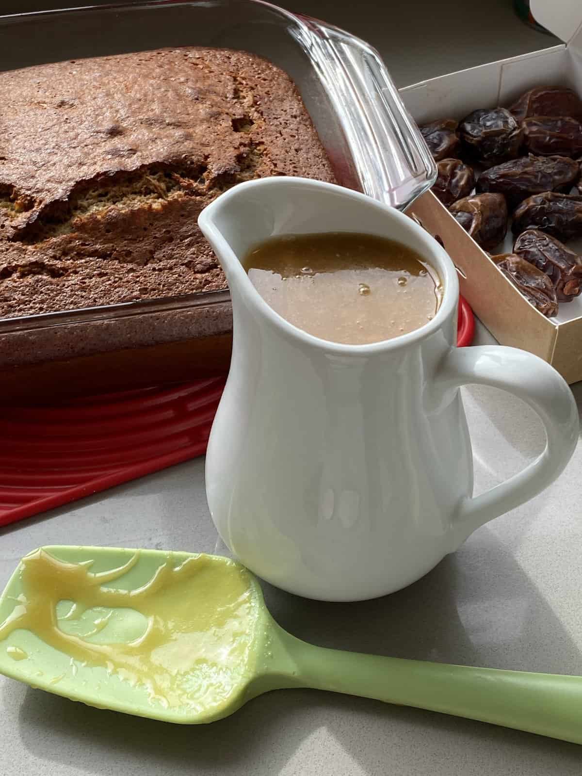 Toffee Pudding and dates, with Toffee Sauce in a white jug.