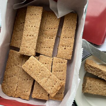 Shortbread biscuits stored in a square tin.